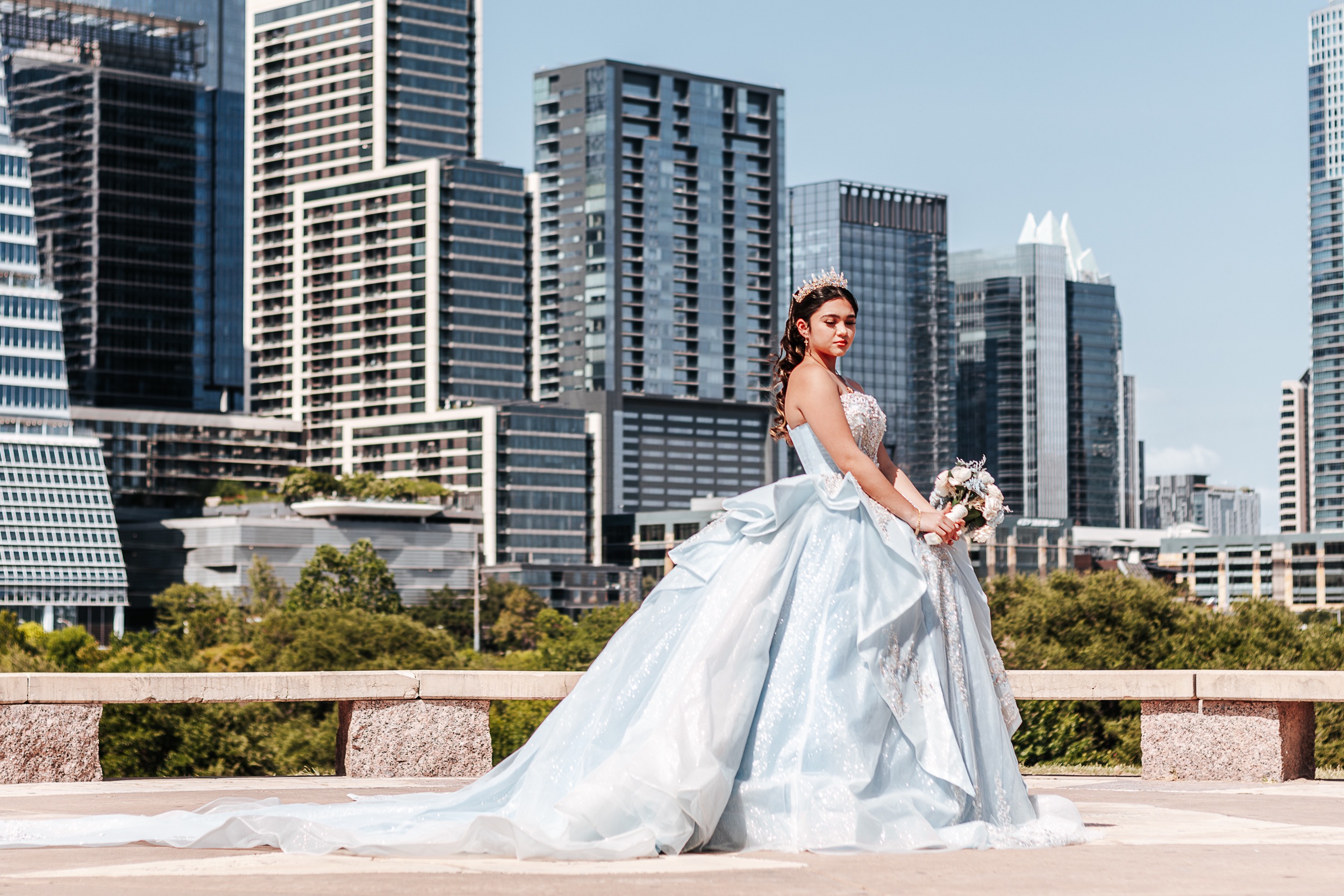 Quinceañera honoree in ice-blue ball gown poses before the Austin city skyline — Austin quinceañera photographer