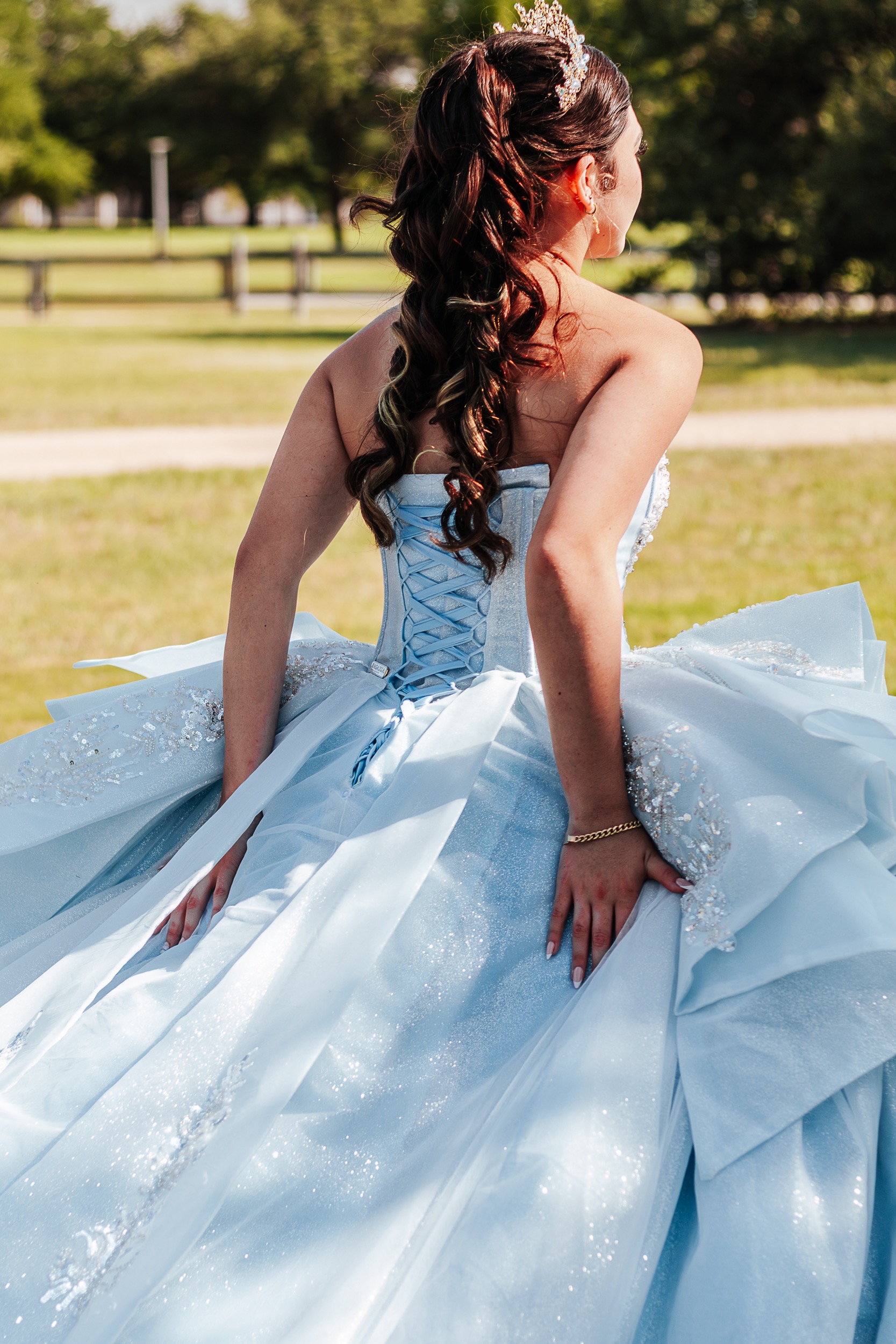 Back view of quinceañera honoree showing intricate lace-up corset of blue sparkle gown