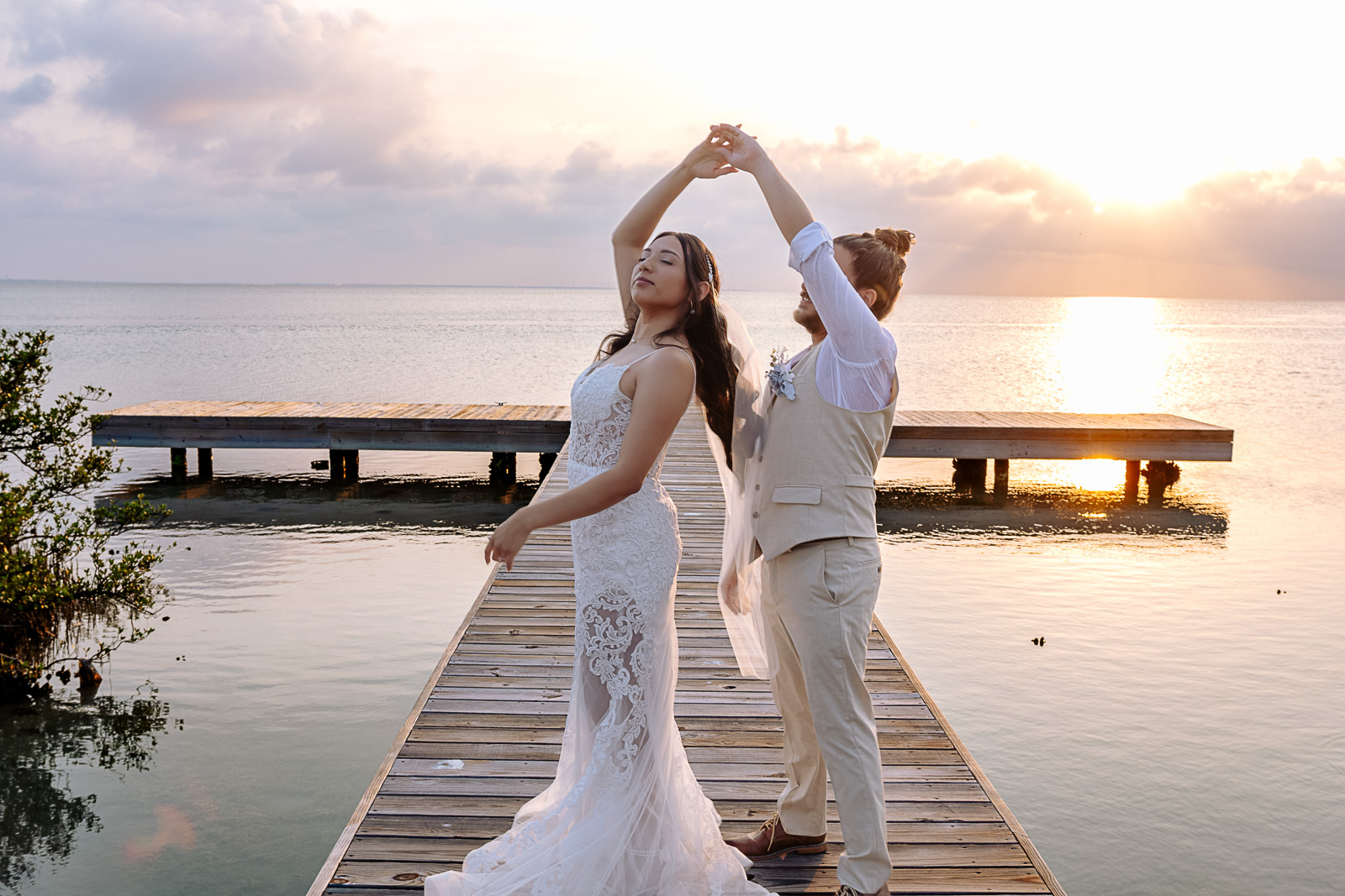 Groom twirls bride in a sweeping lace gown on a dock at sunset — Texas wedding